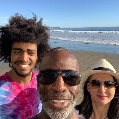 Michael Johnson is takling a selfie and Armine Shamiryan and Sebastian Johnson are standing next to him at the beach.